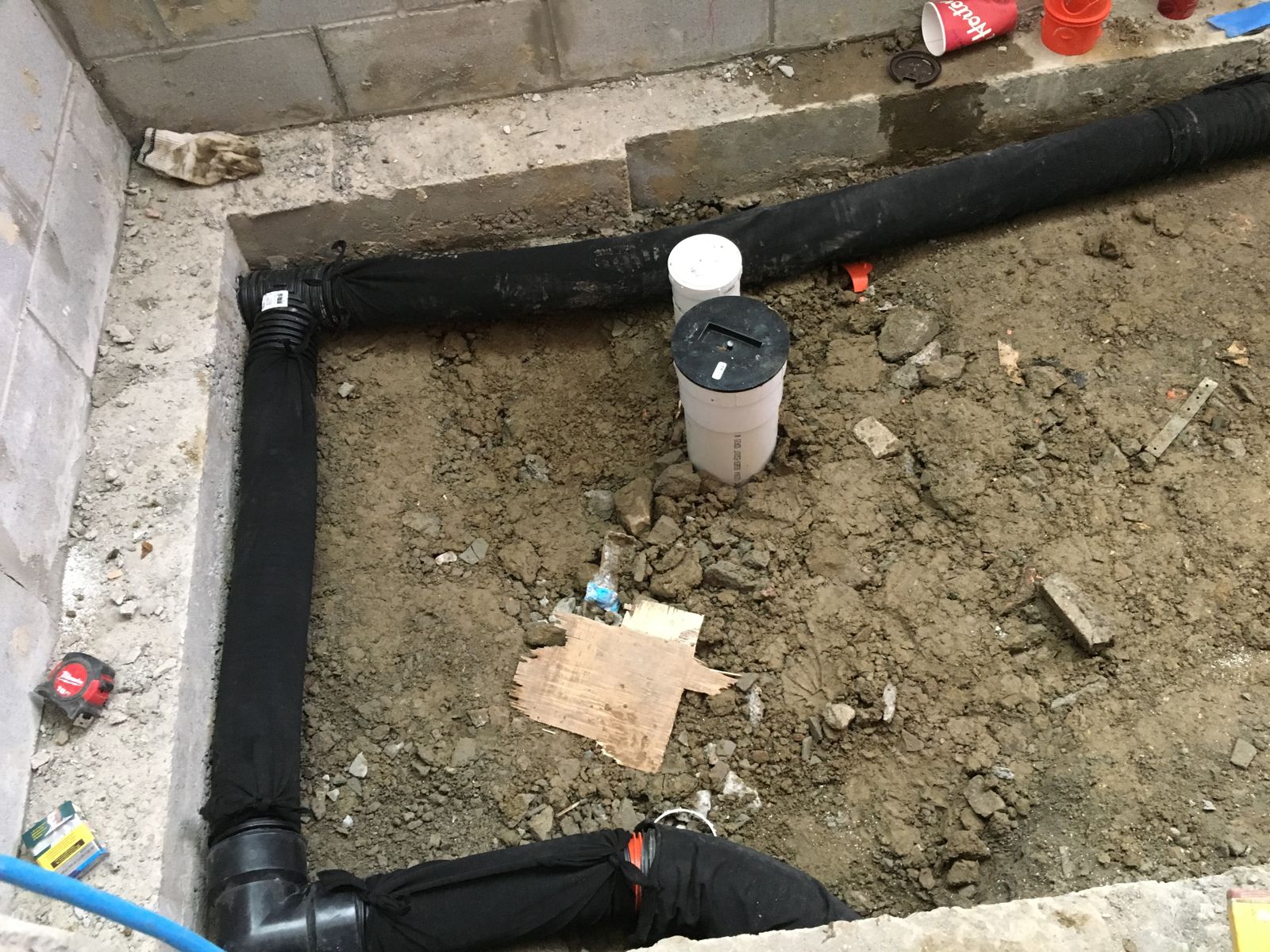Black sock-wrapped weeping tile laid along a basement wall