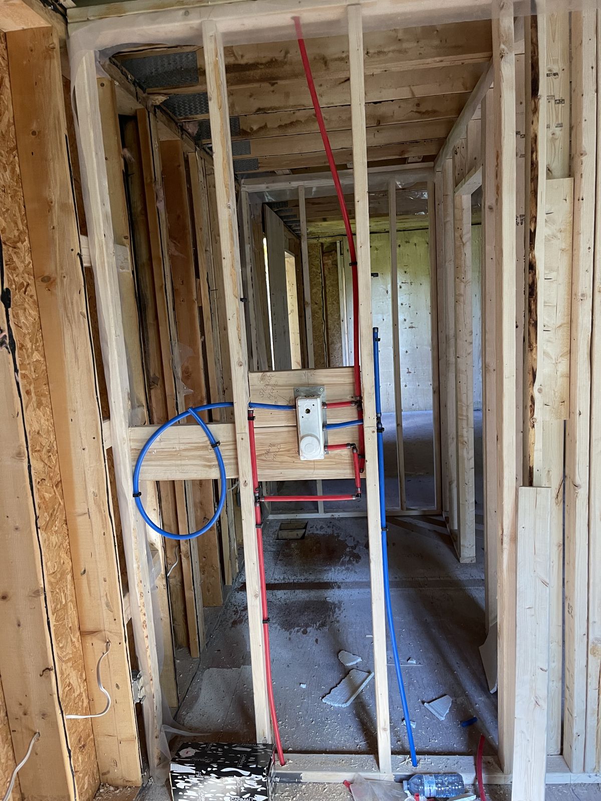 Shower valve roughed in with red and blue PEX lines in a framed wall