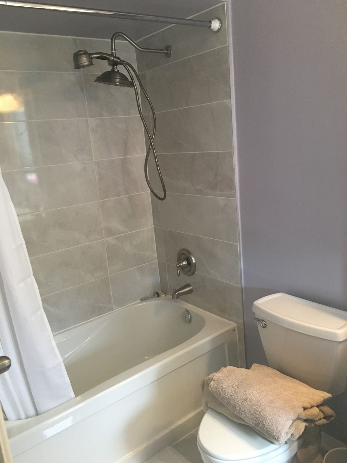 Finished tub surround with brushed-nickel valve, rain head and hand shower